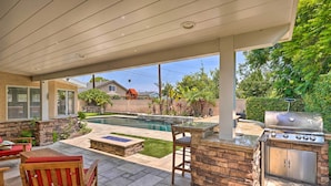 Une terrasse extérieure avec une piscine, un barbecue et des sièges.