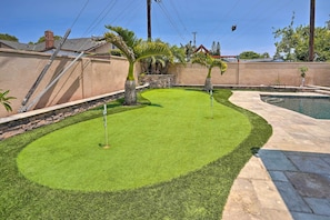 A backyard with a swimming pool, a stone wall, and a well-maintained lawn. - Quiet Anaheim Home w/ Pool, 5 Mi to Disney! (Anaheim)