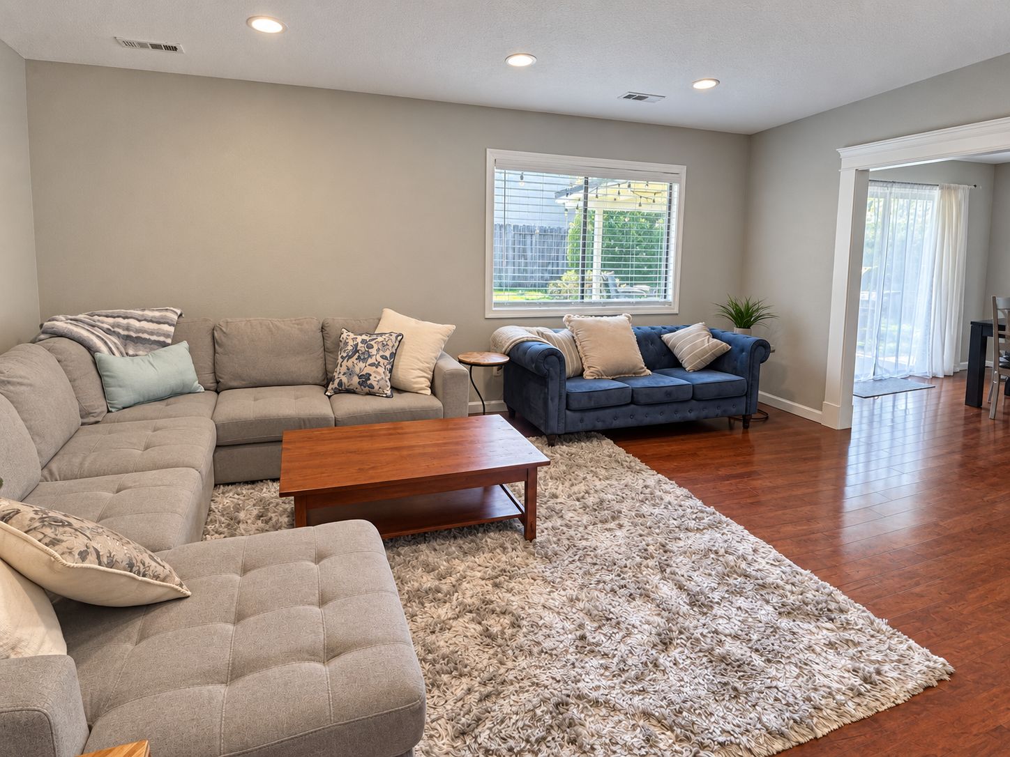 A living room with a sectional sofa, a blue couch, and a coffee table.