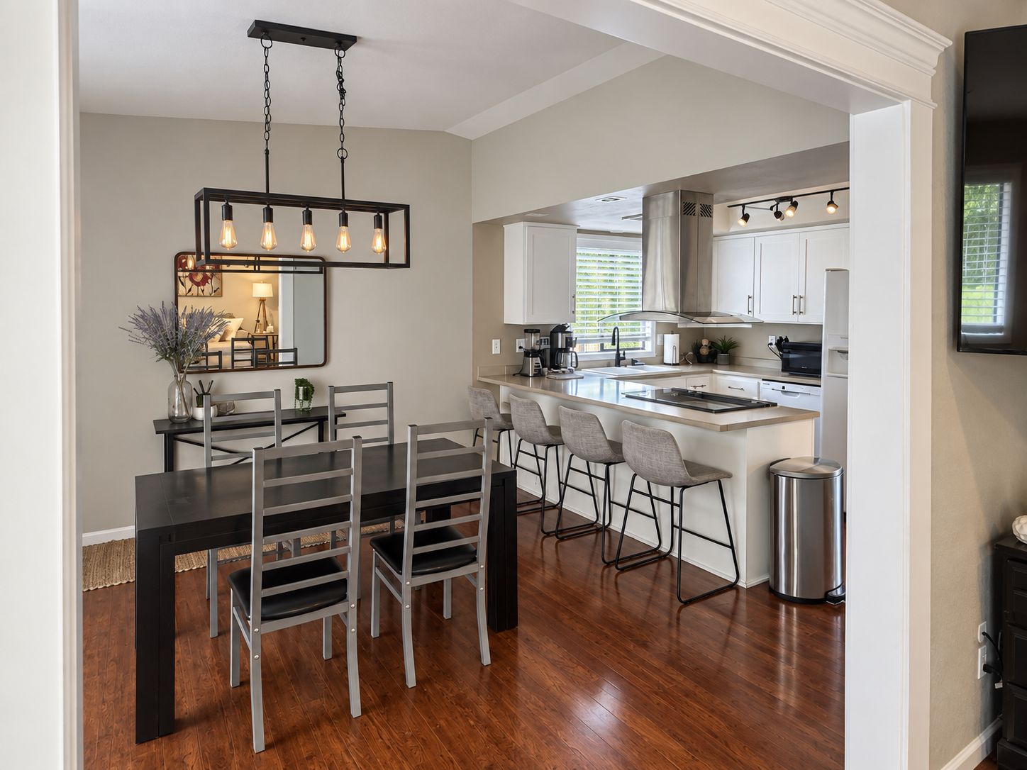 A modern kitchen with white cabinets, a central island, and bar stools.