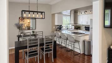 A modern kitchen with white cabinets, a central island, and bar stools.