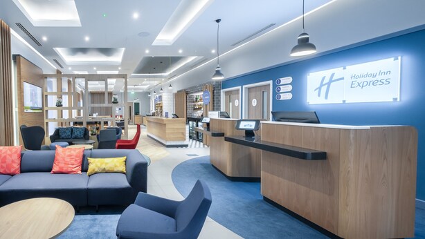 A Holiday Inn Express lobby with a reception desk, seating area, and a bar. - Holiday Inn Express Fleet (Fleet)