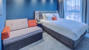 A modern hotel room with a large bed, a sofa, and a desk with a telephone. - Holiday Inn Express Fleet (Fleet)
