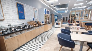 A modern breakfast bar with a variety of food items and a seating area with tables and chairs. - Holiday Inn Express Fleet (Fleet)