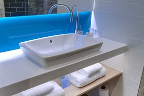 A bathroom with a white sink, a blue bathtub, and a shelf with towels.
