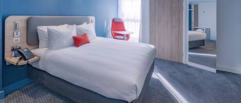 Une chambre d’hôtel moderne avec un grand lit, un téléphone sur la table de chevet, une chaise rouge et un miroir.