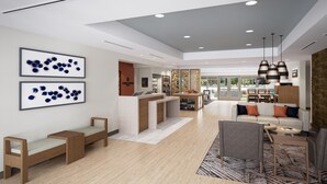 A modern hotel lobby with a reception desk, seating area, and artwork on the walls.