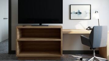 A modern office space with a large flat-screen TV, a desk, a chair, and a shelf unit.