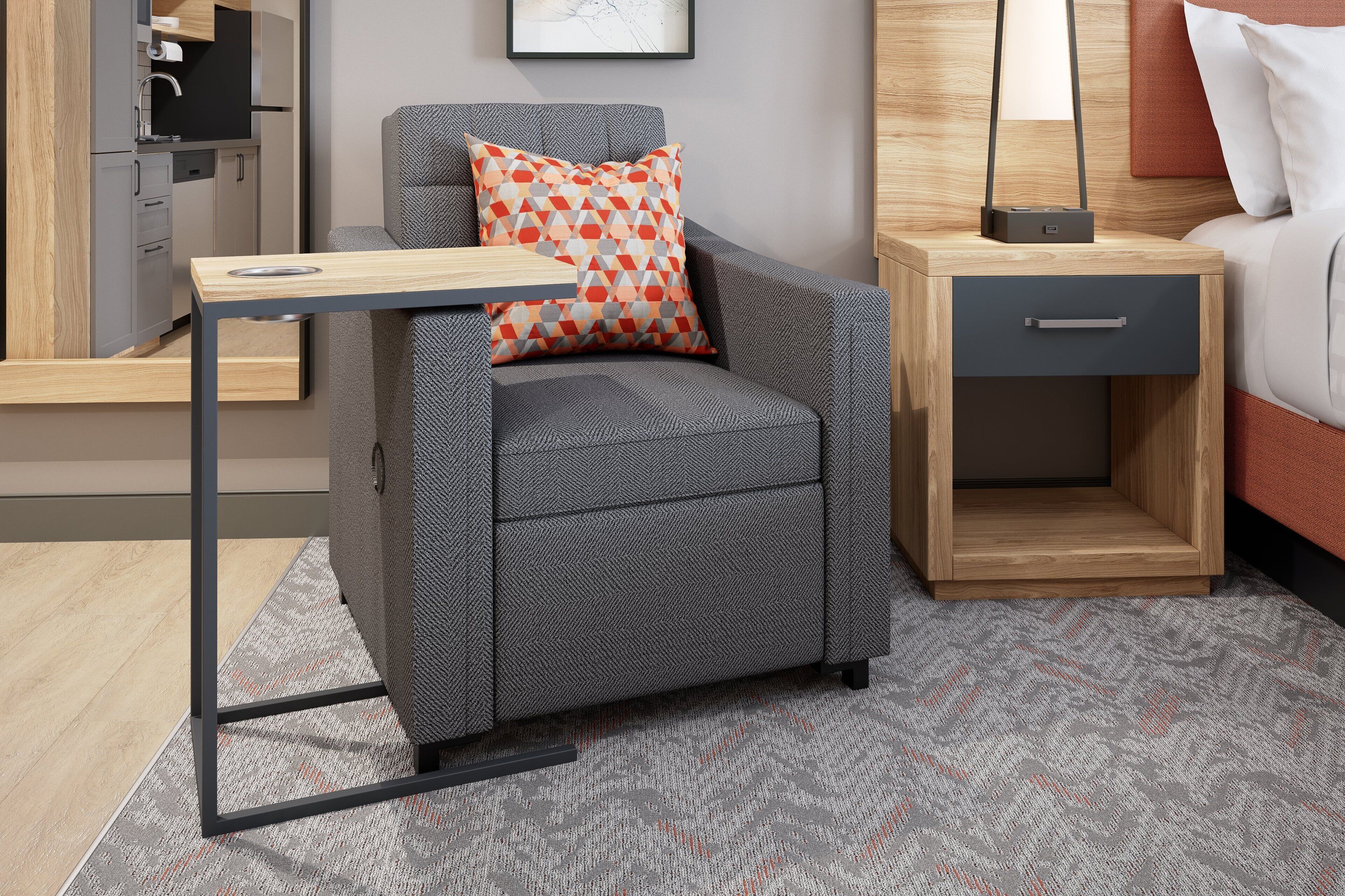 Habitación compacta con sofá gris, una pequeña mesita de madera, un cajón y una cama con cabecera.