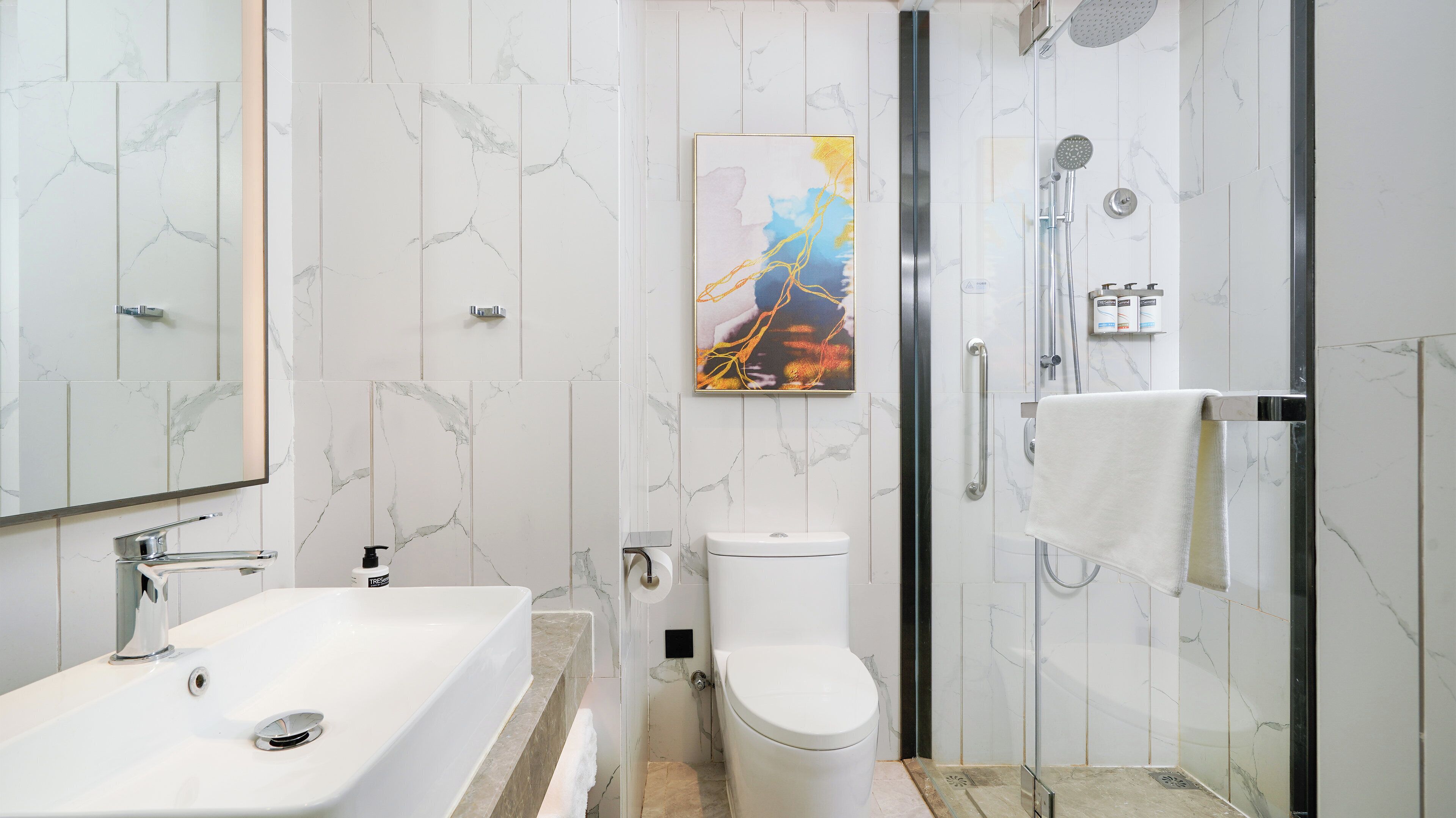 A modern bathroom with a white marble sink, a toilet, and a shower area.