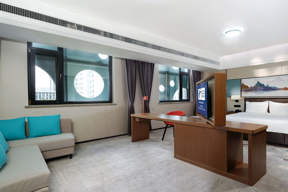 A hotel room with a bed, a desk, a sofa, and a TV.