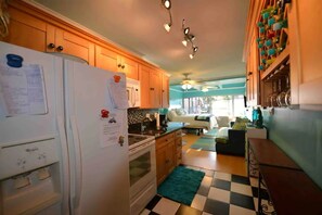 A kitchen with wooden cabinets, a white refrigerator, a stove, and a checkered floor.