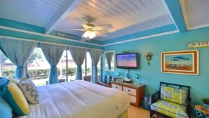 Ein Schlafzimmer mit Bett, Fernseher, Sessel und Deckenventilator.