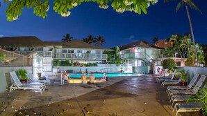 Ein Hotel mit Poolbereich, Liegestühlen und Palmen.