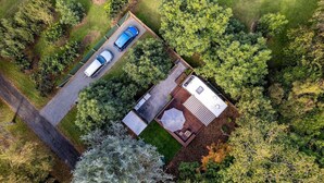 Luchtbeeld van een pand met een huis, een oprit en twee geparkeerde auto's.