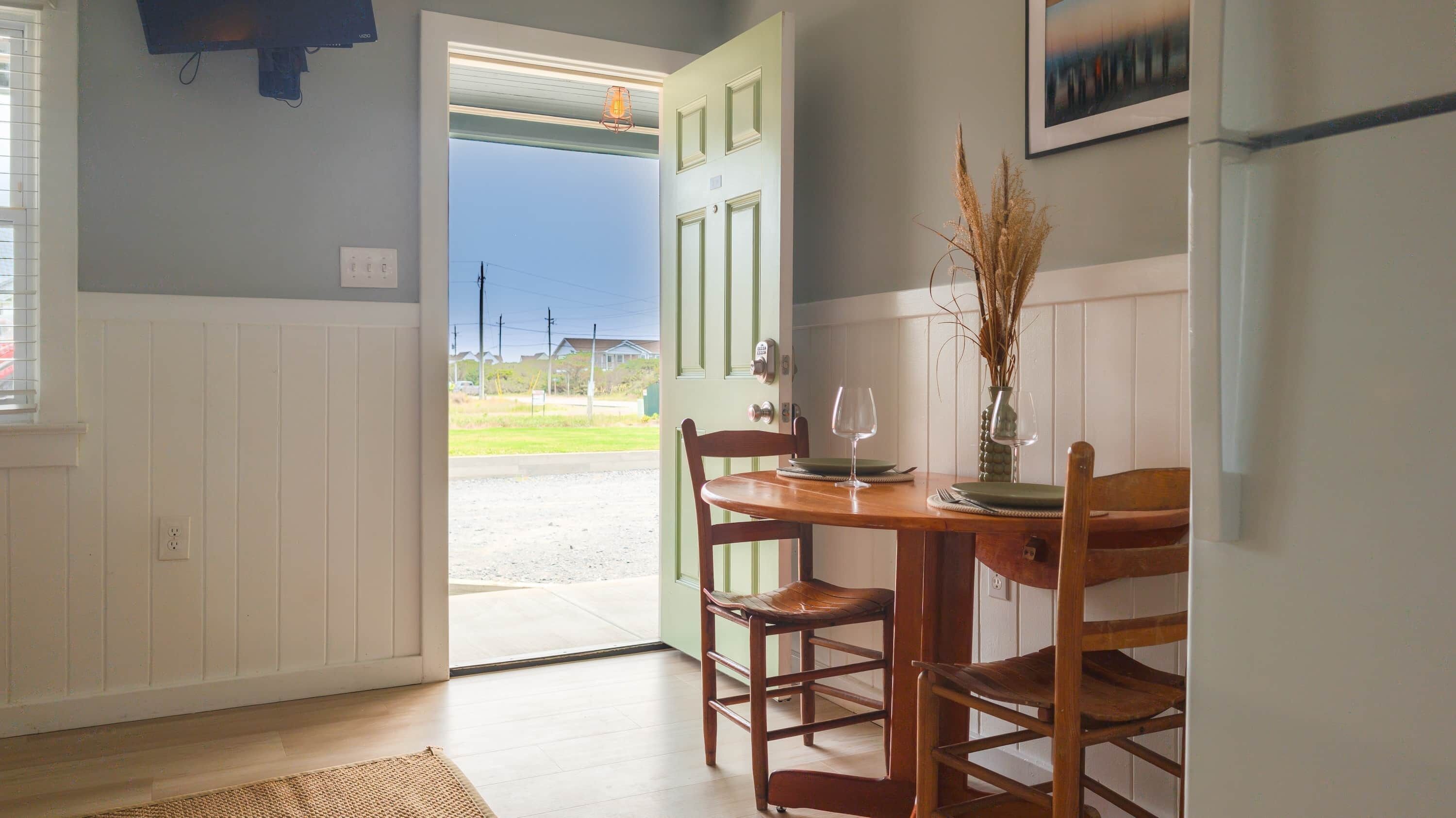 A dining area with a wooden table, chairs, and a vase with dried plants.