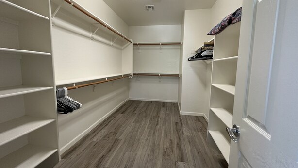 Un vestidor amplio con repisas abiertas y piso de madera.