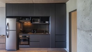 Una cocina moderna con refrigerador de acero inoxidable, horno empotrado, microondas y cafetera.