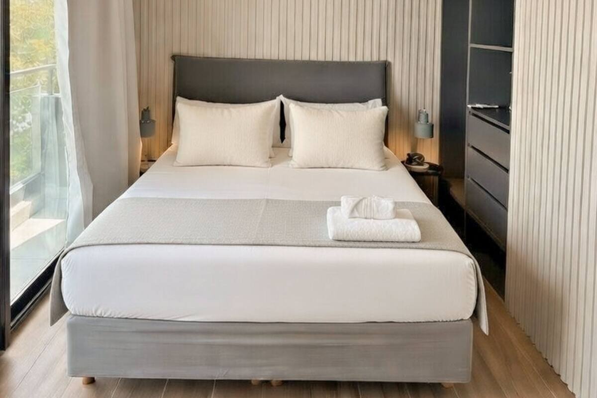 Una habitación de hotel moderna con una cama grande, vistas al exterior y un armario empotrado.