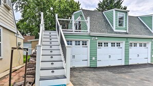A residential property with a green garage, white garage doors, and a staircase leading to a deck. - Epic Brunswick Apartment with Hot Tub! (Brunswick)
