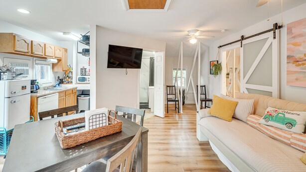 A modern kitchen with wooden cabinets, a dining table, and a sofa with striped cushions. - Epic Brunswick Apartment with Hot Tub! (Brunswick)