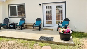 A house with a covered porch, two chairs, a small table, and a potted plant.
