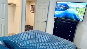 A bedroom with a bed, a dresser, and a TV displaying a scenic landscape.