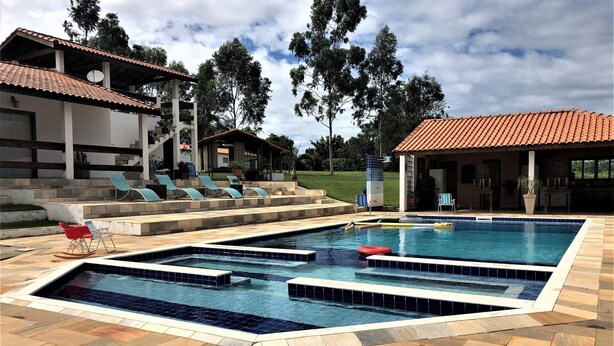 Una piscina con varias pistas de natación, sillas de descanso y una zona de estar cubierta.