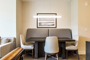 A modern dining area with a dark wood table and two grey upholstered chairs. - LIFT 509 | True Ski-In / Ski-Out Luxury | Steps to Sunrise Gondola (Park City)
