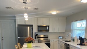 A modern kitchen with white cabinets, stainless steel appliances, and a central island with bar stools.