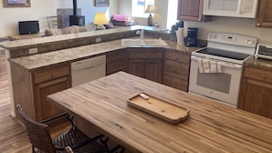 Une cuisine dotée de plans de travail en granit, de meubles en bois, d’un lave-vaisselle encastré, d’une cuisinière et d’un four à micro-ondes.