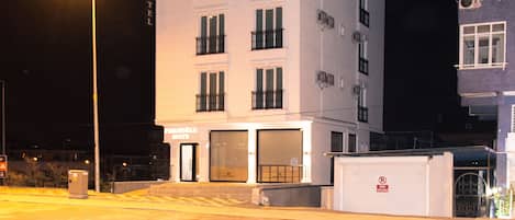 A white building with the sign 'FIDANOGLU SUITE HOTEL' and multiple windows.