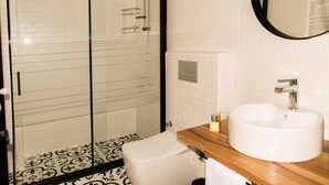 Un bagno con doccia vetrata, lavandino bianco e piano d'appoggio in legno.