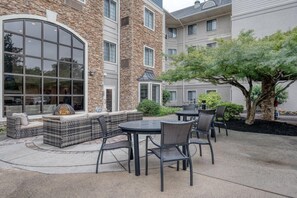 An outdoor patio with seating, a fire feature, and a tree.