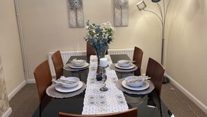 Ein Essbereich mit einem schwarzen Tisch, weißen Tellern und einer Blumenvase.