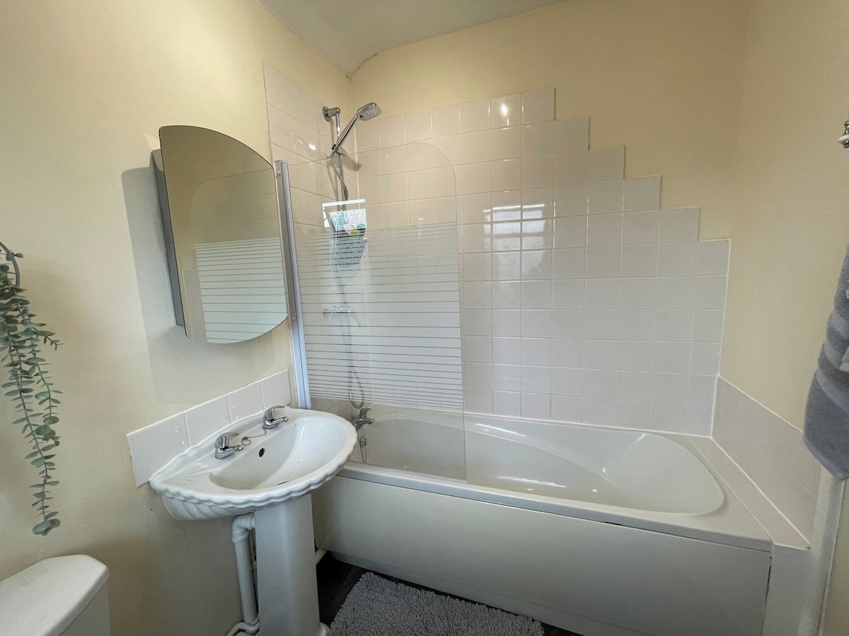 A bathroom with a bathtub, a sink, and a mirror.