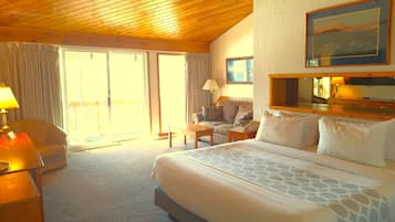 Una habitación de hotel con una cama grande, un sofá, un escritorio y un balcón con cortinas.
