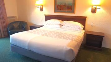 A hotel room with a large bed, two bedside tables, a chair, and two wall-mounted lamps.