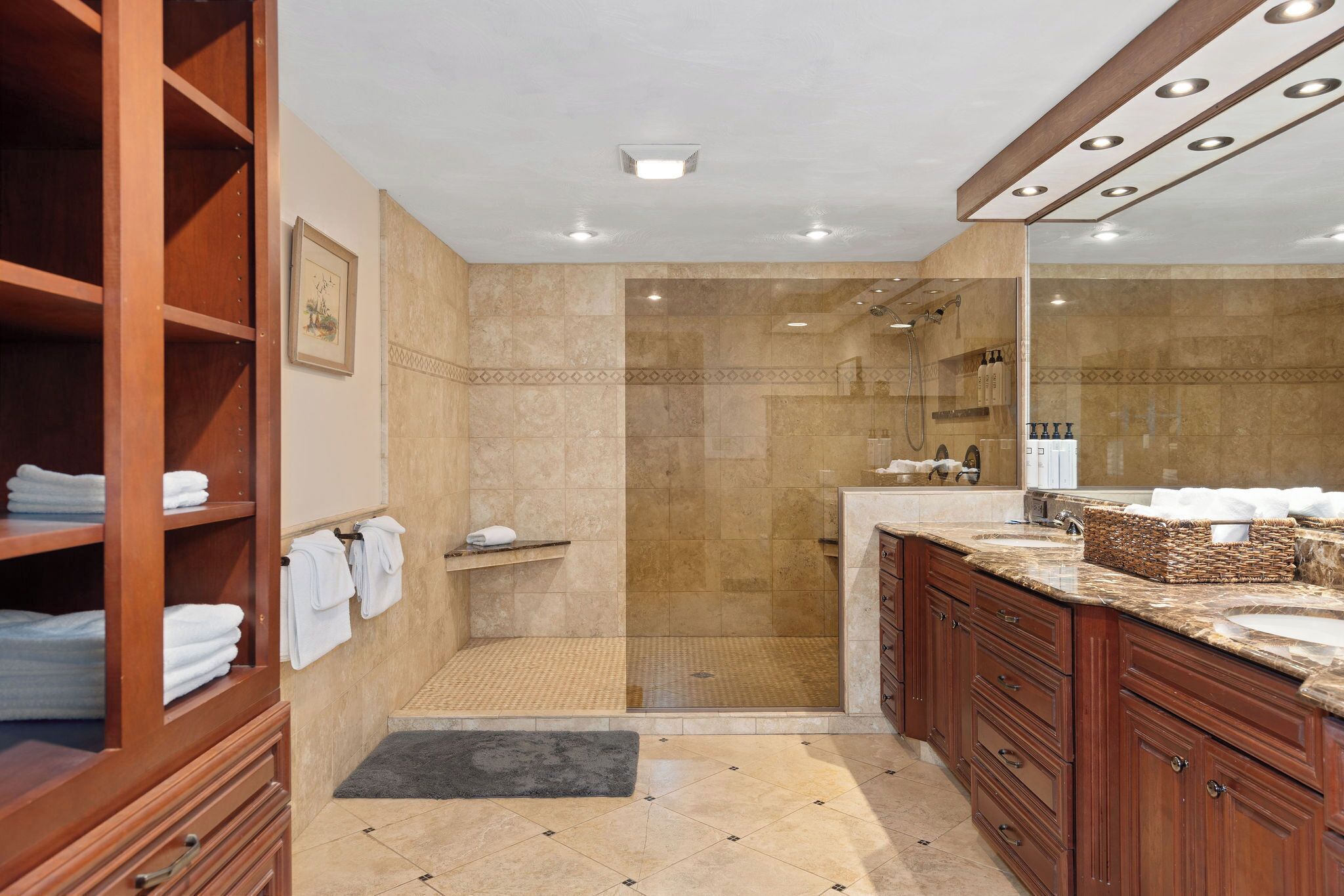 Un baño moderno con cabina de ducha, tocador de madera y un espejo grande.