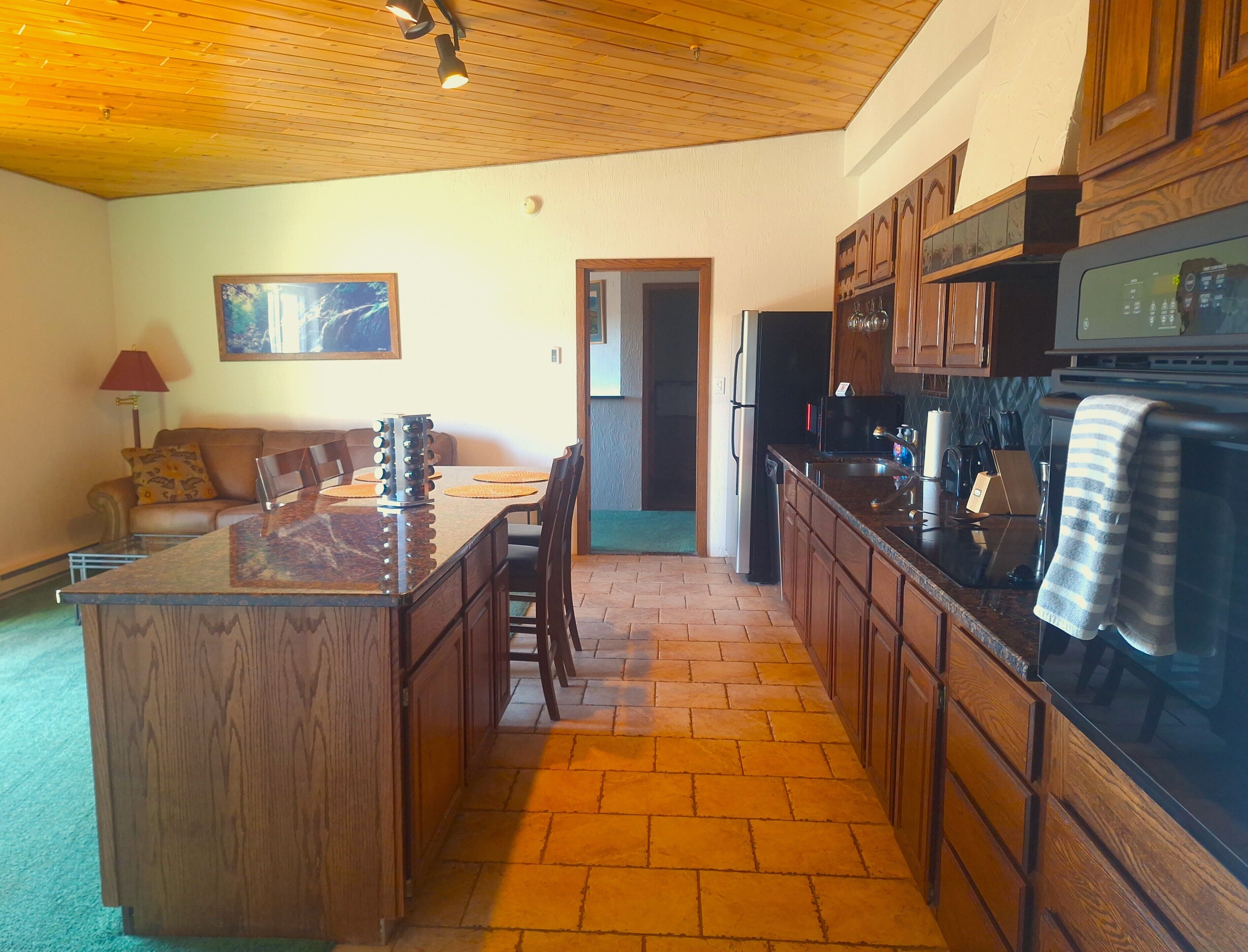 A kitchen with wooden cabinets, a granite countertop, and a built-in oven.