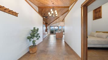 Un pasillo con techo de madera, una planta en maceta y vista a una zona de cocina.