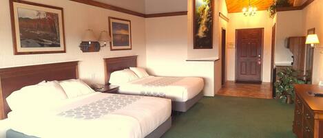 Een hotelkamer met twee bedden, een houten plafond en een groen tapijt.