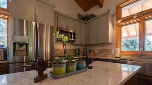 Cocina moderna con electrodomésticos de acero inoxidable, encimera de granito y ventana que proporciona luz natural.