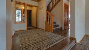 Una escalera de madera que conduce a un segundo piso, una alfombra en el suelo y una puerta con la palabra 'JOY' escrita en ella.
