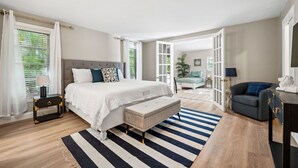 Une chambre à coucher comprenant un lit, une table de chevet, un banc et donnant sur un espace de vie.