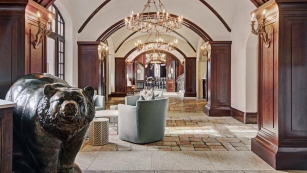 Un'imponente sala con un lampadario, una scultura di un orso e un pavimento in pietra.