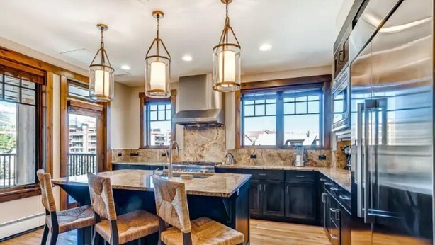 A modern kitchen with a central island, pendant lights, and a large refrigerator. - Luxury 4 Bedroom Condo on Main Street in Downtown Breckenridge (Breckenridge)
