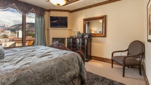 A bedroom with a large bed, a dresser, a chair, a mirror, and a TV. - Vail Arrabelle 3 Bedroom Residence (Vail)