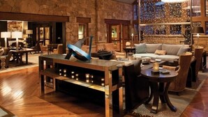Un vestíbulo espacioso con pared de piedra, una gran mesa de centro de madera y una zona de estar con sofá y sillones.