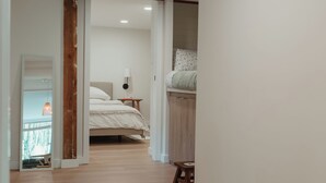 Un couloir menant à une chambre à coucher équipée d’un lit, d’une table de chevet et d’une armoire.